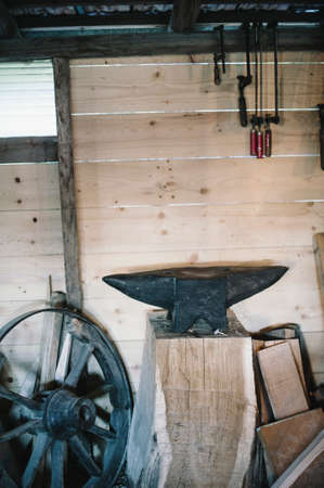 carpentry workshop with anvil and other tools and old wagon wheelの写真素材