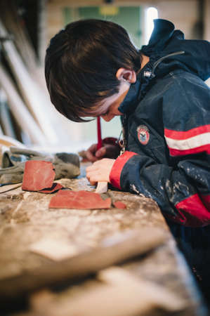 10-year-old boy in a carpenter's workshop learns to do small jobs, manual jobs