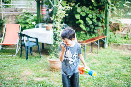 children play in the garden with guns and water rifles on a sunny summer day having a lot of fun