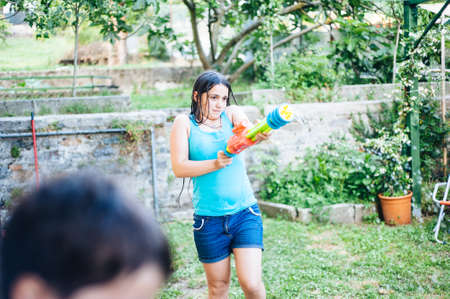children play in the garden with guns and water rifles on a sunny summer day having a lot of fun