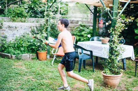 children play in the garden with guns and water rifles on a sunny summer day having a lot of fun