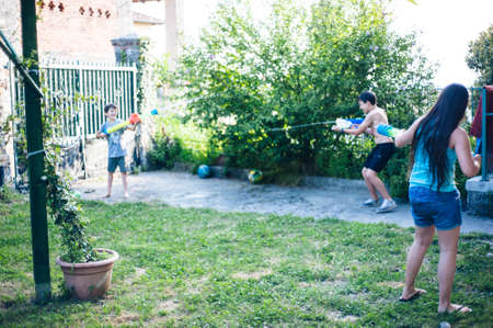 children play in the garden with guns and water rifles on a sunny summer day having a lot of funのeditorial素材
