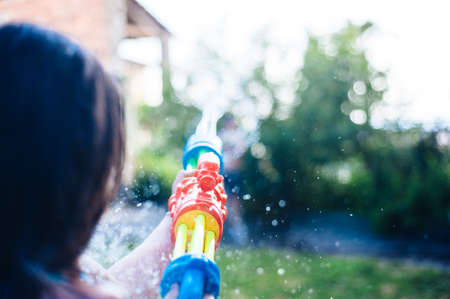 children play in the garden with guns and water rifles on a sunny summer day having a lot of fun