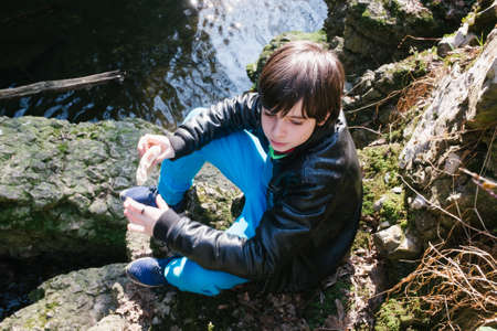 12 year old boy eating sandwich outside in natureの写真素材