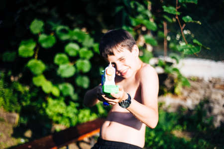 children play in the garden with guns and water rifles on a sunny summer day having a lot of funの写真素材