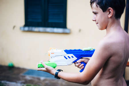 children play in the garden with guns and water rifles on a sunny summer day having a lot of funの写真素材