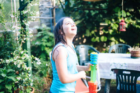 children play in the garden with guns and water rifles on a sunny summer day having a lot of funの写真素材