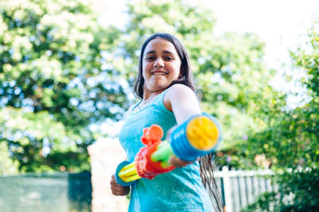 children play in the garden with guns and water rifles on a sunny summer day having a lot of funの写真素材
