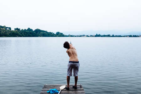 12 year old boy fishing on lake pierの写真素材