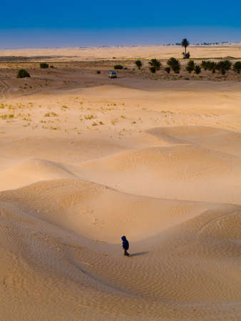 child in the Sahara desert plays with the sand of the dunes, tourist on vacation, Douz Tunisiaの写真素材