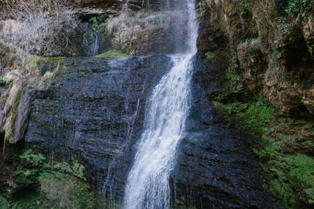 big waterfall in spring, water flows into a small lake between the rocksの写真素材