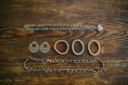 necklaces bracelets and earrings of costume jewelery spread over dark wood
