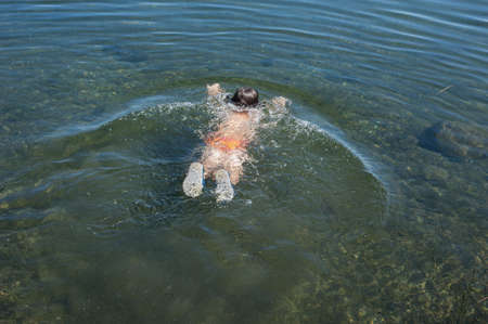child swims in the lake in the summerの写真素材