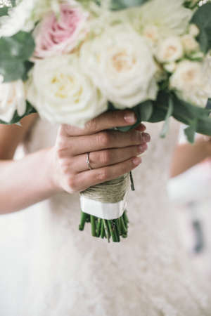 young bride holds in her hands her bouquette of white and pink roses on her wedding day, close up viewの写真素材
