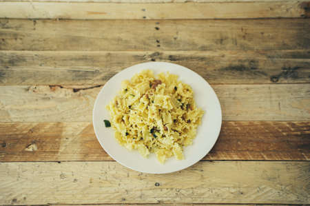 short mafalde pasta dish with sausage and zucchini, rough wood background