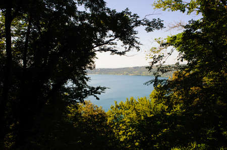 view of the lake of Albano among the branches of the trees, tourist area of the Roman castles, Rome Italyの写真素材