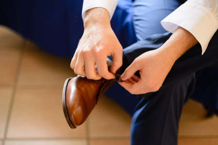 elegantly dressed classic man fastens the strings of the shoesの写真素材