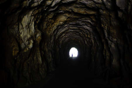 rock tunnel in the mountain human figure at the bottom in the light