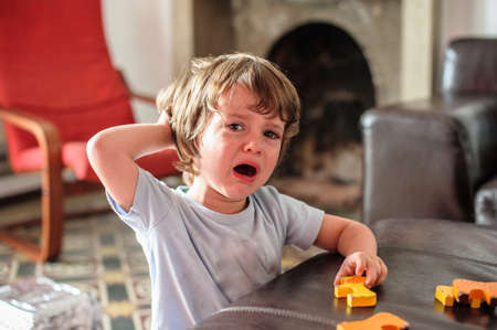 child cries with tears on his face while playing at home