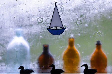 Colorful bottles lined up in front of a steamy glass window following a hot sauna in a cabin on the Finnish Archipelago.の写真素材