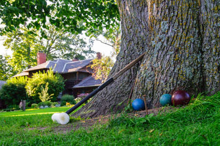 Croquet mallet and balls leaning against a tree, waiting to play の写真素材