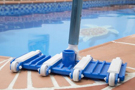 Wall Brush and Leaf Skimmer Maintenance Tools on Deck Beside Swimming Pool