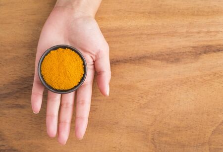 Turmeric powder in bowl between hands - Curcuma longaの写真素材