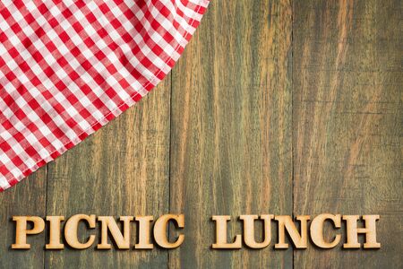 Picnic lunch - Wooden background with checkered napkin. Letters in wood
