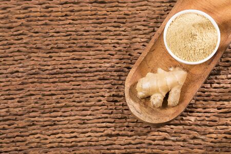 Fresh sliced ginger root and ground ginger on wooden background - Zingiber officinale
