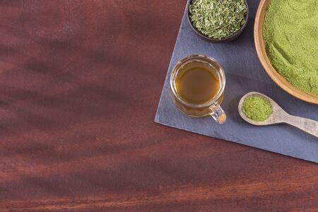 Moringa tea with powder and leaves - Moringa oleifera. Wooden background