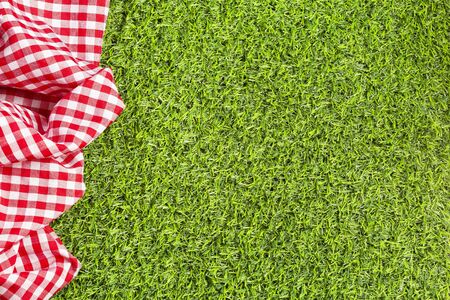 Red checkered napkin on the green grass. Background for design