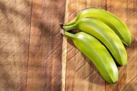 Bunch of green bananas on wooden background - Musa x paradisiacaの写真素材