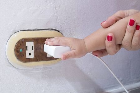 The boy puts his fingers in the electrical socket. Dangerous situation at home