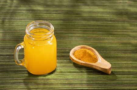 Spoon with turmeric powder to mix with water - Curcuma longa