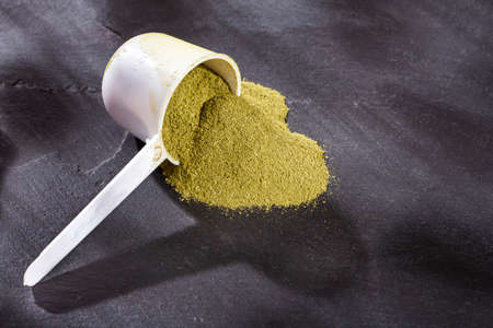 Organic green powder in measuring spoon - text space