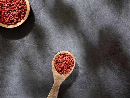 Organic achiote seeds in wooden spoon - Bixa Orellanaの写真素材