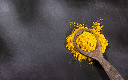 Organic curry powder in wooden spoon - Text spaceの写真素材