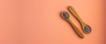 Organic poppy seeds in two wooden spoons - Papaver somniferum.の写真素材