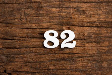 Number 82 in wood, isolated on rustic backgroundの写真素材