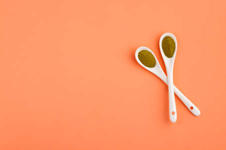 Organic green powder in two ceramic spoons - Moringa