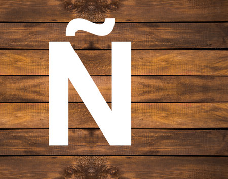 Ã capital letter of alphabet in white hole on wood backgroundの写真素材
