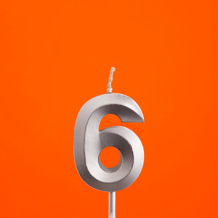 Number 6 - Silver anniversary candle on orange colored backgroundの写真素材