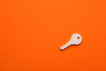 Single key on orange color background - Real estate concept, flat graphic resource for designの写真素材
