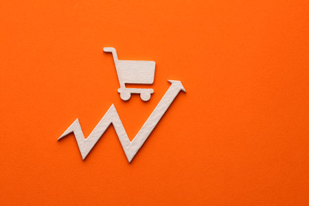 White supermarket cart with up arrow on orange background - Concept of increasing foodの写真素材