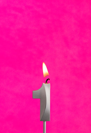 Candle 1 with flame - Silver anniversary candle on a fuchsia backgroundの写真素材