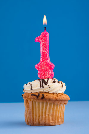 Birthday cake with pink candle number 1 - Blue colored backgroundの写真素材