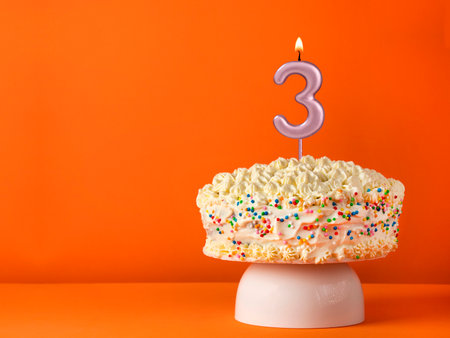 Birthday card with candle number 3 - Vanilla cake in orange backgroundの写真素材