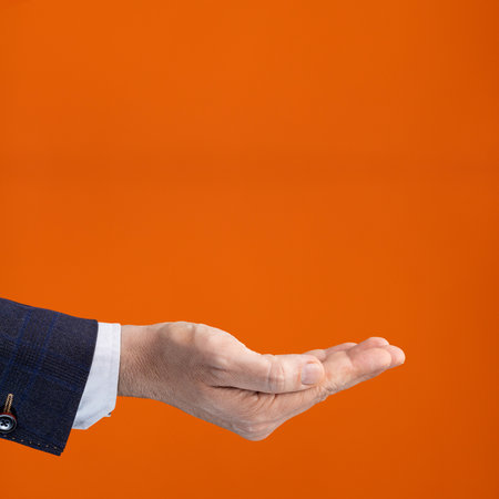 Empty businessman hand on orange color backgroundの写真素材