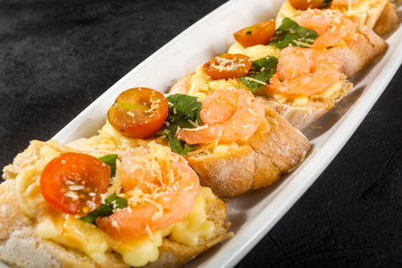 Starter or antipasto dish. Shrimp bruschetta sautÃ©ed in wine on French bread with Neapolitan sauce, basil, mozzarella cheese, cherry tomatoesの写真素材