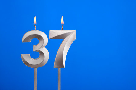 Birthday candle number 37 - Celebration card on blue backgroundの写真素材
